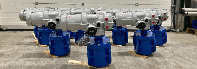 Actuated eccentric plug valves arranged on workshop floor in triangle shape.