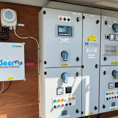An open T-T pump control panel showing wiring and a remote monitoring SEER monitoring unit.